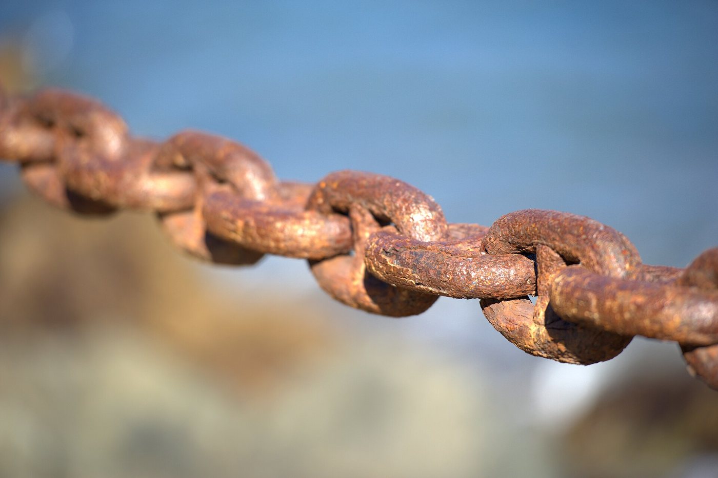 Close-up of rusty steel links of a safety chain in the Presidio, San Francisco, against a softly blurred background.